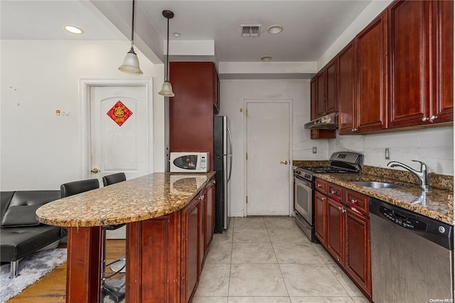 kitchen with dark stone counters, sink, a breakfast bar area, decorative backsplash, and stainless steel appliances