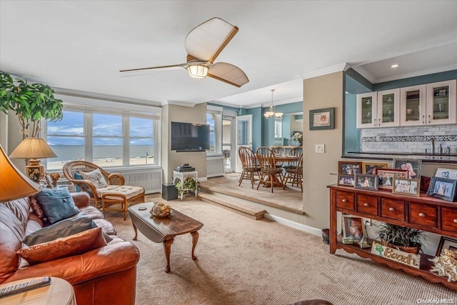 living room featuring carpet, ceiling fan with notable chandelier, and ornamental molding