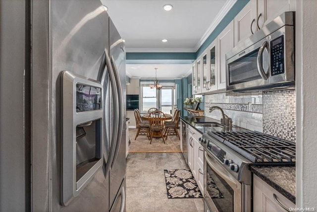 kitchen featuring white cabinets, sink, appliances with stainless steel finishes, tasteful backsplash, and a notable chandelier