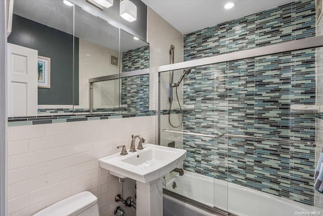 bathroom with shower / bath combination with glass door, tile walls, and toilet