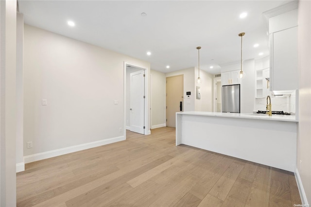 kitchen with pendant lighting, stainless steel refrigerator, white cabinetry, light hardwood / wood-style floors, and kitchen peninsula