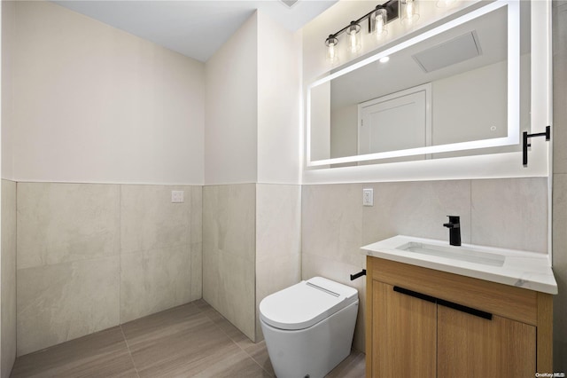 bathroom with vanity, toilet, and tile walls