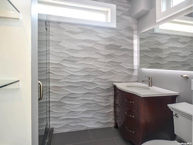 bathroom featuring tile patterned floors, vanity, toilet, and a shower with door