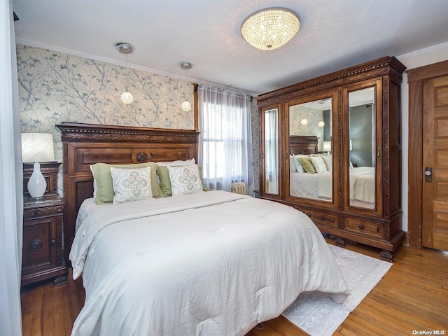 bedroom featuring hardwood / wood-style flooring, an inviting chandelier, and ornamental molding