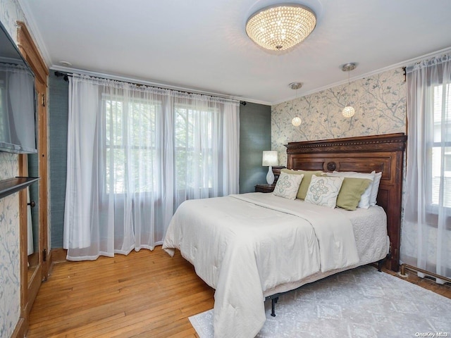 bedroom with crown molding, an inviting chandelier, and hardwood / wood-style flooring