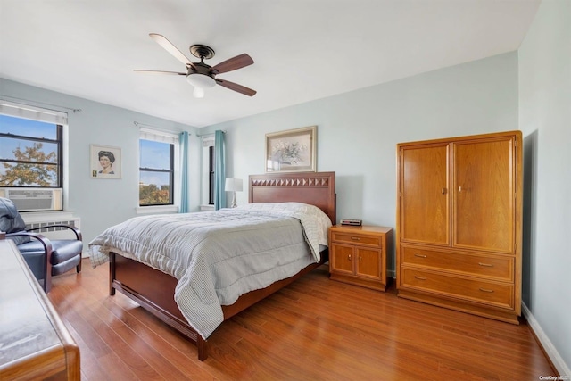 bedroom featuring ceiling fan, cooling unit, and wood-type flooring