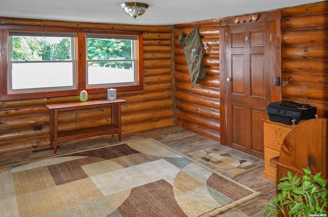 entryway with log walls, wood-type flooring, and a textured ceiling