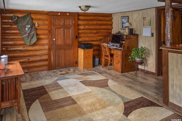 interior space featuring a textured ceiling, rustic walls, and hardwood / wood-style floors