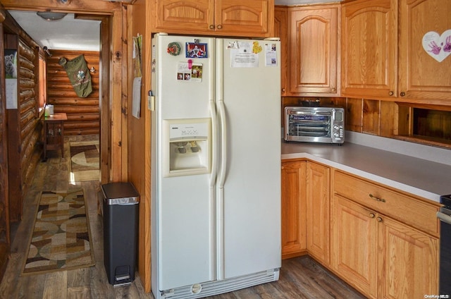 kitchen featuring white refrigerator with ice dispenser, dark hardwood / wood-style floors, and rustic walls