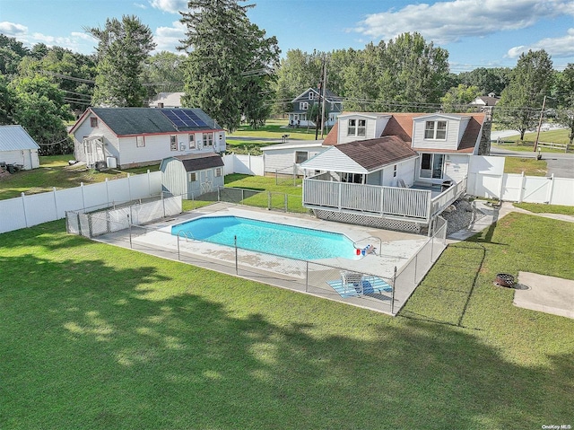 view of swimming pool featuring a lawn, a deck, and a storage unit