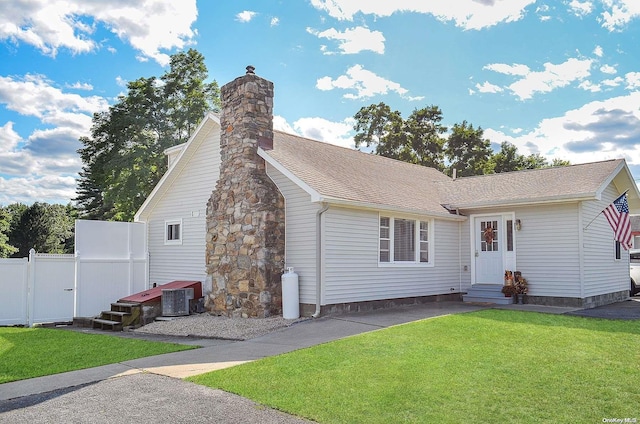 view of front of house with central air condition unit and a front lawn