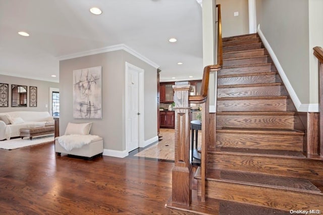 stairs with hardwood / wood-style floors and crown molding