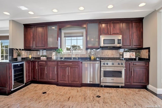 kitchen featuring a wealth of natural light, sink, beverage cooler, and stainless steel appliances