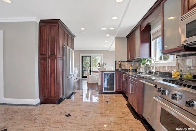 kitchen featuring decorative backsplash, appliances with stainless steel finishes, beverage cooler, sink, and dark stone countertops