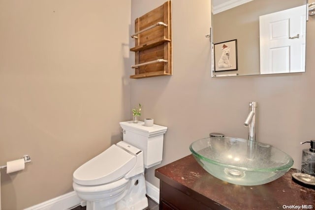 bathroom with vanity, toilet, and ornamental molding