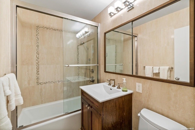 full bathroom with shower / bath combination with glass door, vanity, tile walls, and toilet