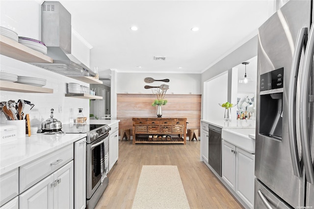 kitchen with wall chimney exhaust hood, white cabinetry, stainless steel appliances, and hanging light fixtures