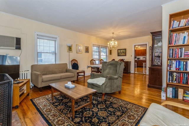 living room with a chandelier, hardwood / wood-style flooring, a wall unit AC, and radiator