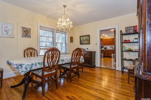 dining room with crown molding, an inviting chandelier, and hardwood / wood-style flooring