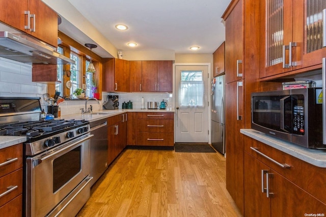 kitchen with sink, stainless steel appliances, light hardwood / wood-style flooring, ventilation hood, and backsplash