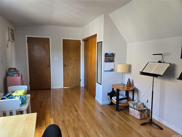 interior space featuring a wall mounted AC, light hardwood / wood-style flooring, and lofted ceiling