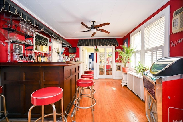 bar with hardwood / wood-style floors, ceiling fan, a wall mounted air conditioner, and ornamental molding