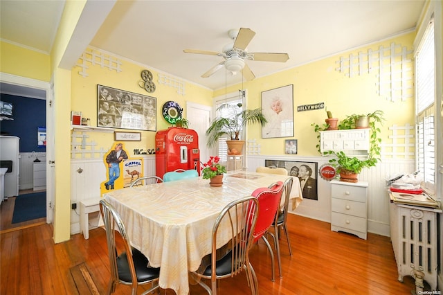 dining space with radiator, ceiling fan, wood-type flooring, and ornamental molding