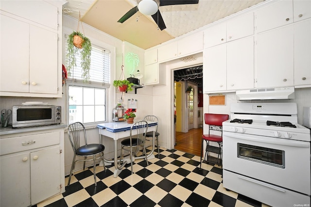 kitchen featuring white range with gas cooktop, ceiling fan, and white cabinets