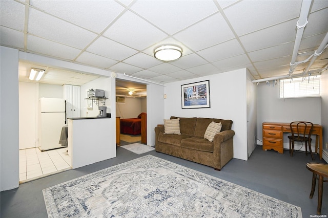 living room with a paneled ceiling, baseboard heating, and concrete floors