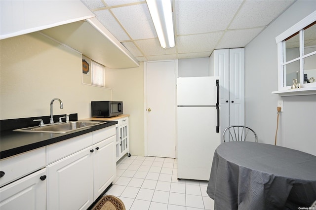 kitchen featuring white cabinets, a paneled ceiling, white refrigerator, and sink