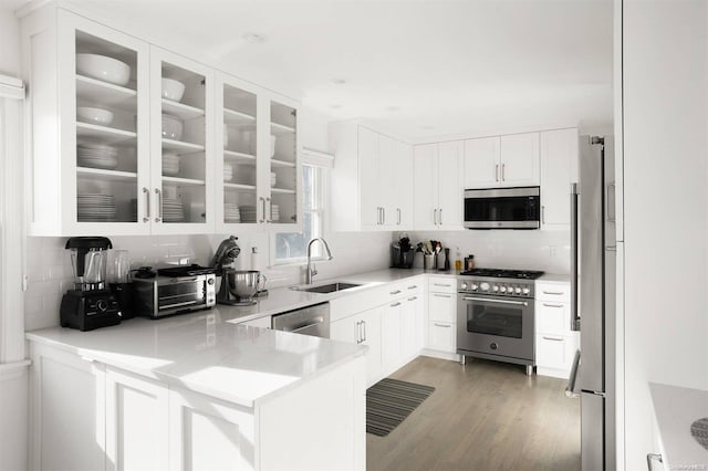 kitchen featuring decorative backsplash, sink, high quality appliances, white cabinets, and light hardwood / wood-style floors