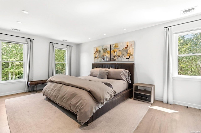 bedroom with multiple windows and light hardwood / wood-style flooring