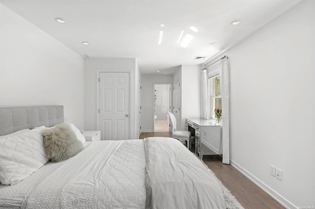 bedroom with ensuite bathroom and dark hardwood / wood-style floors