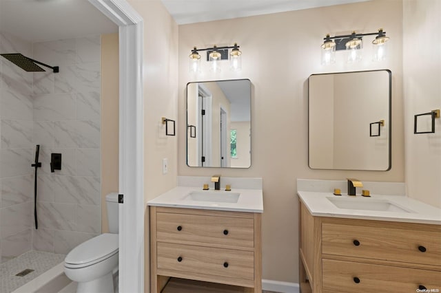 bathroom with tiled shower, vanity, and toilet