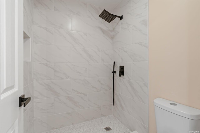 bathroom with a tile shower and toilet