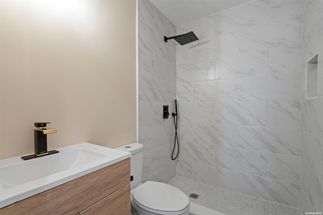 bathroom with vanity, toilet, and a tile shower