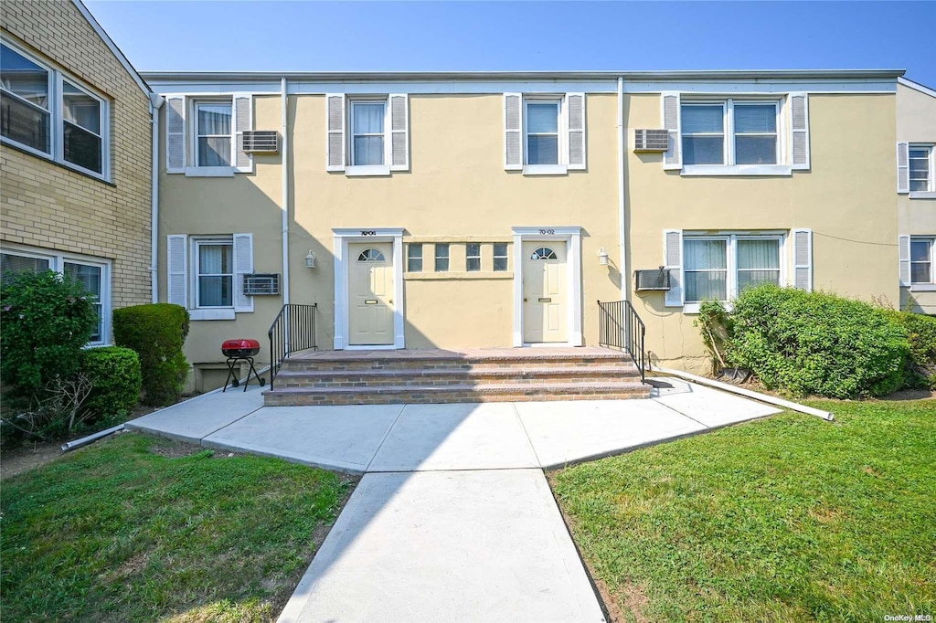 view of front of property with a front yard and an AC wall unit