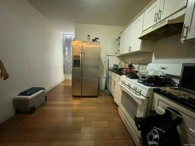 kitchen featuring stainless steel appliances, dark countertops, under cabinet range hood, and white cabinets