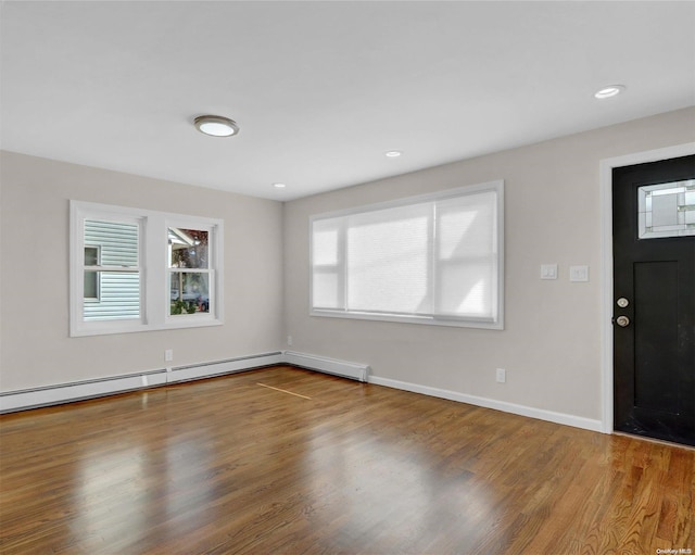 foyer entrance with wood-type flooring and a baseboard heating unit