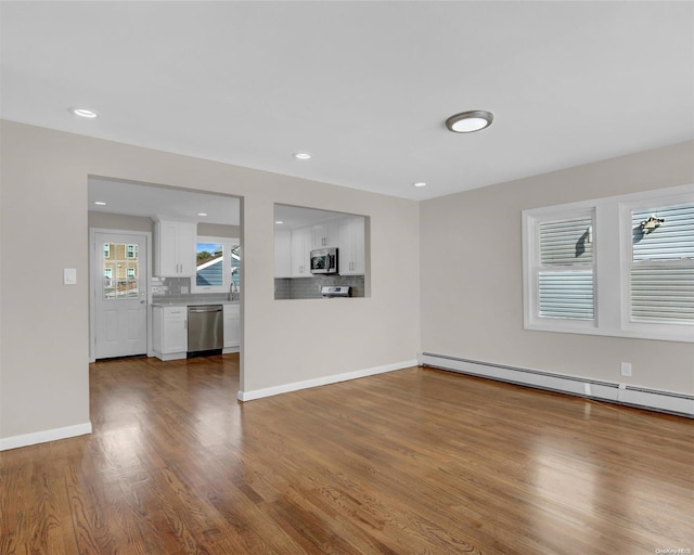 unfurnished living room featuring hardwood / wood-style floors and baseboard heating