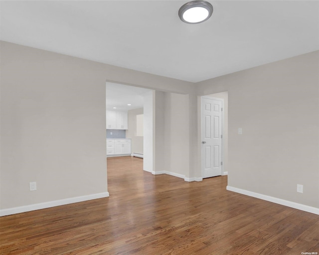 empty room featuring hardwood / wood-style flooring and a baseboard radiator