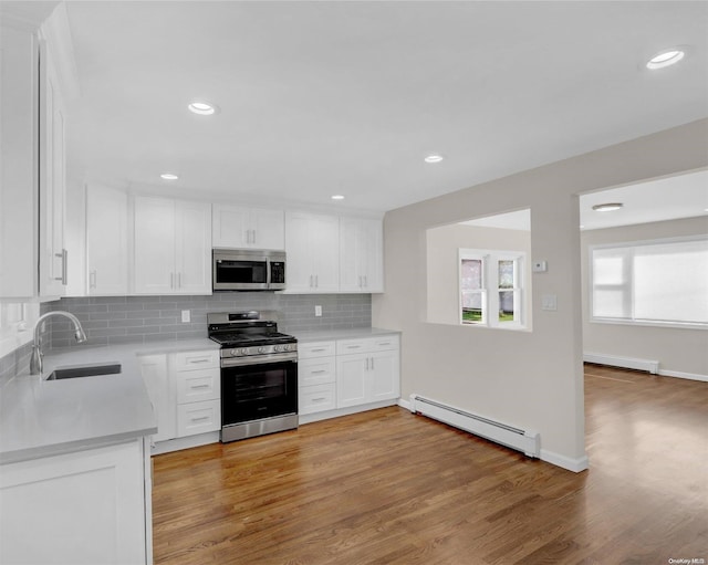 kitchen with white cabinets, light hardwood / wood-style flooring, stainless steel appliances, and a baseboard radiator