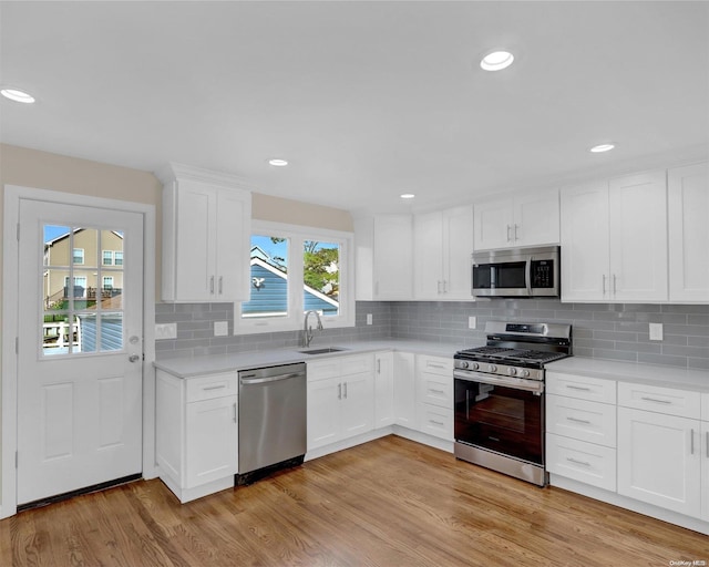 kitchen featuring white cabinetry, sink, appliances with stainless steel finishes, and light hardwood / wood-style flooring