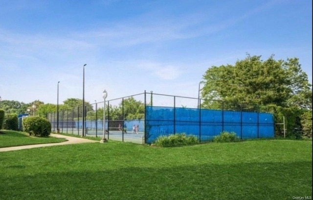 view of tennis court featuring a lawn