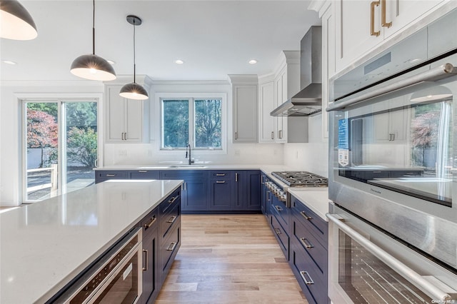 kitchen with white cabinetry, wall chimney range hood, sink, and appliances with stainless steel finishes