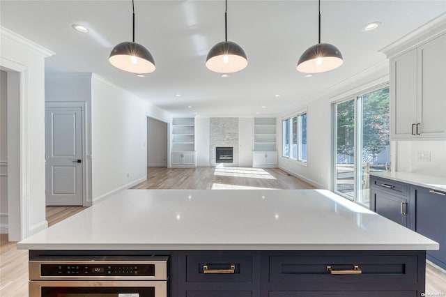 kitchen with a fireplace, a center island, light wood-type flooring, and hanging light fixtures