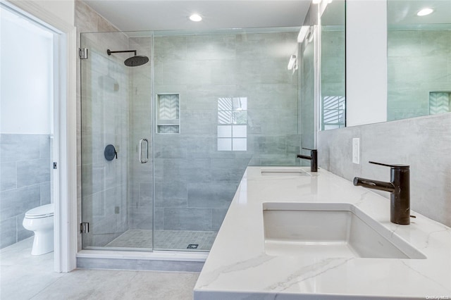 bathroom with walk in shower, tile patterned floors, toilet, vanity, and tile walls