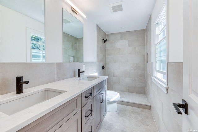 bathroom with tiled shower, toilet, and tile walls