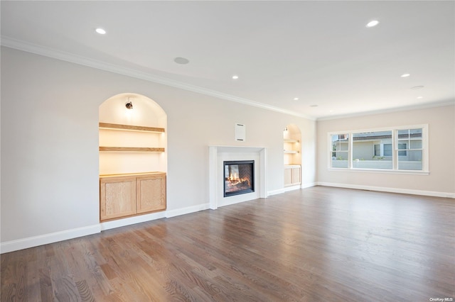 unfurnished living room with dark hardwood / wood-style flooring, built in features, and crown molding