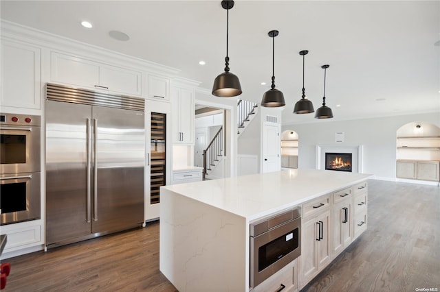 kitchen featuring built in appliances, decorative light fixtures, dark hardwood / wood-style flooring, and white cabinetry